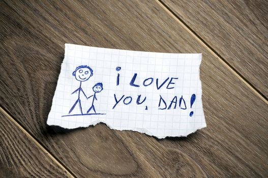 I love you, Dad written on piece of paper, on a wood background