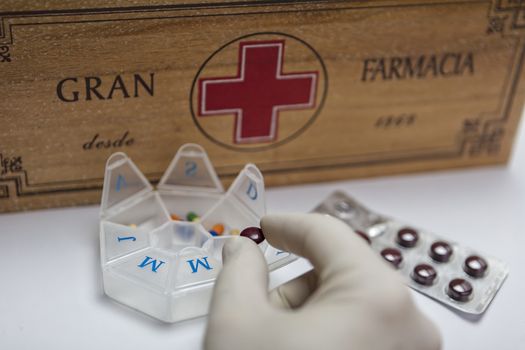 Pills with pill organizer next to old wood kit