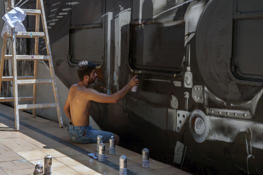 Bucharest, Romania - June 29, 2013:  A young graffiti artist during drawing and painting his artwork in Train Delivery Fest on 29 June, 2013 in Bucharest, Romania