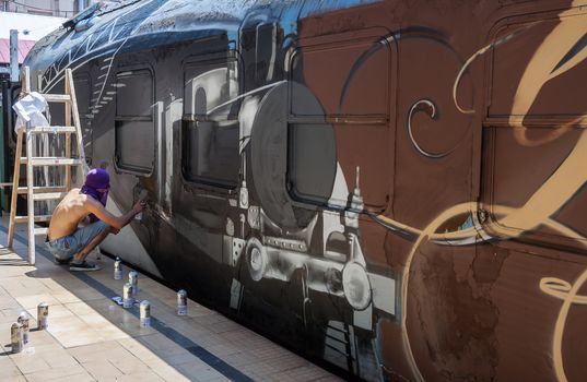 Bucharest, Romania - June 29, 2013:  A young graffiti artist during drawing and painting his artwork in Train Delivery Fest on 29 June, 2013 in Bucharest, Romania