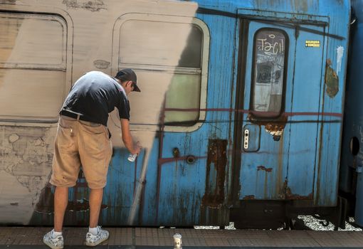 Bucharest, Romania - June 29, 2013:  A young graffiti artist during drawing and painting his artwork in Train Delivery Fest on 29 June, 2013 in Bucharest, Romania