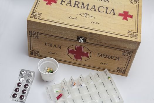 Pills with pill organizer next to old wood kit