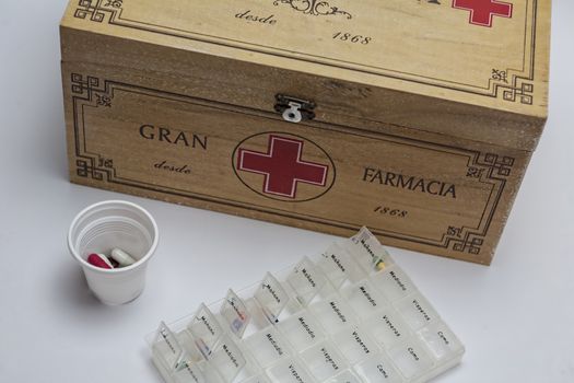 Pills with pill organizer next to old wood kit