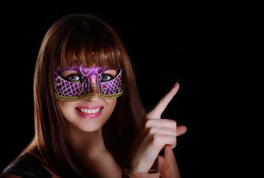 Beautiful caucasian brunette in carnival mask over black background