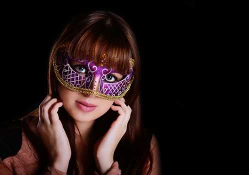 Beautiful caucasian brunette in carnival mask over black background