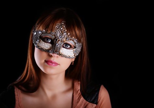 Beautiful caucasian brunette in carnival mask over black background