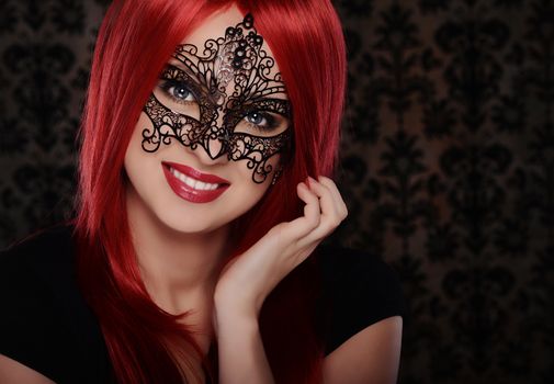 Beautiful caucasian red haired woman in carnival mask over blue background