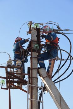 Electricians working at height on a support with linear disconnector and cable XLPE 