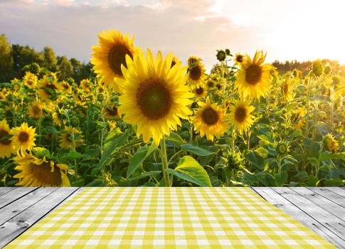 Empty wooden table and yellow sunflowers field in background