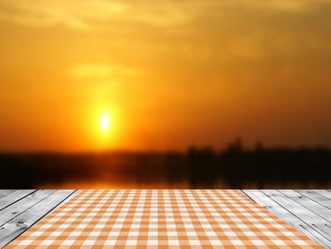 Empty wooden table and sunset sky in background