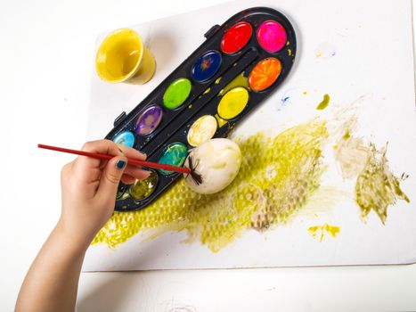 Little girls hands playing with colorful paint, creating Easter decoration