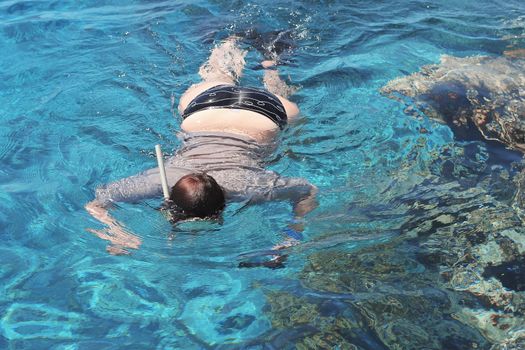Woman photographer diving into water of Red sea