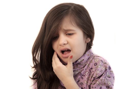 Cute little girl with her hand held to her face with painful expression showing toothache