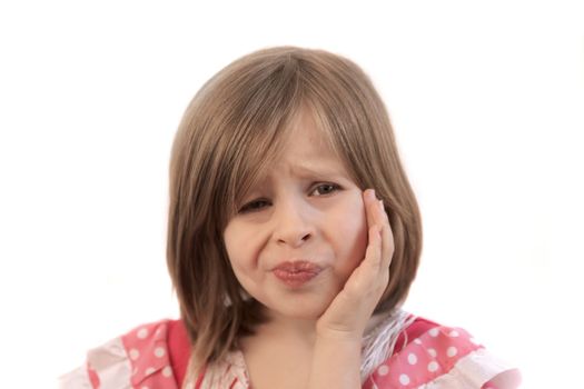 Cute little girl with her hand held to her face with painful expression showing toothache ( shallow depth of field )
