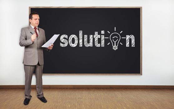 businessman standing in office and blackboard with solution symbol