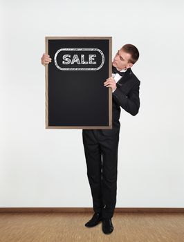 businessman standing in office and  holding blackboard with sale