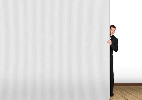 businessman looking out from behind a concrete wall