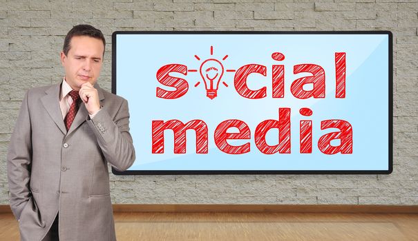 businessman thinking and big plasma with social media on wall