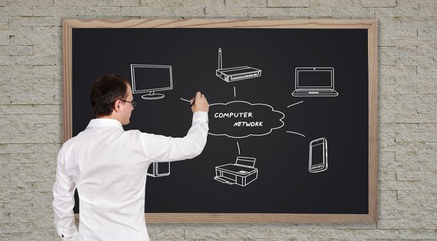 young businessman drawing computer network on blackboard