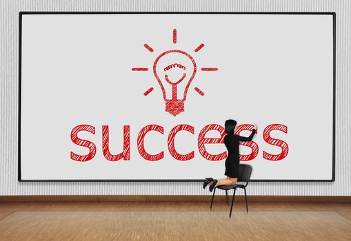 woman standing on a chair and drawing success symbol