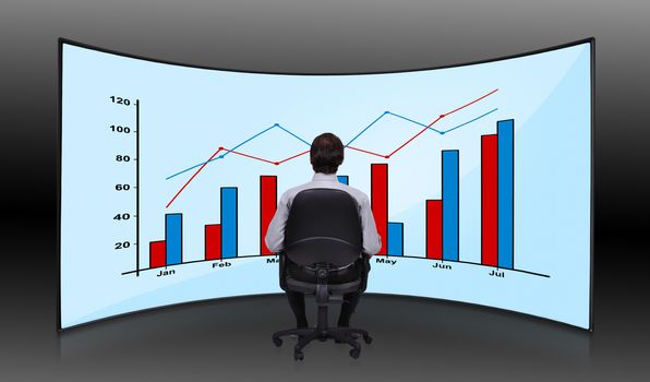 businessman sitting in movie house and looking at plasma with chart