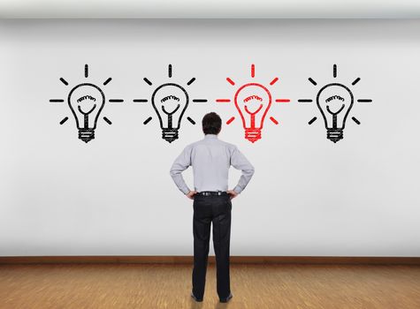 businessman in office looking at wall with lamps