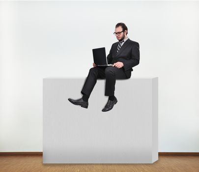 businessman sitting on concrete wall in room
