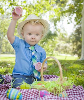 Cute Little Boy Wearing Hat Enjoying His Easter Eggs on Picnic Blanket Outside in the Park.