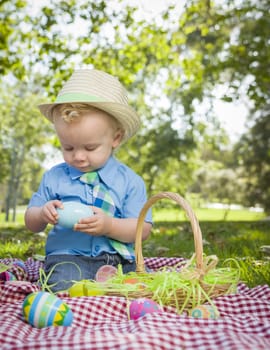 Cute Little Boy Wearing Hat Enjoying His Easter Eggs on Picnic Blanket Outside in the Park.