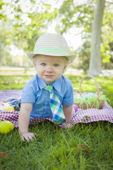 Cute Little Boy Smiles on Picnic Blanket With Easter Eggs Around Him.