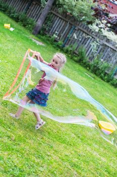 Little girl making giant soap bubble in outside