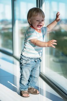 Happy baby boy standing on the windowsill