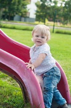 Smiling child playing on a baby slide outdoors