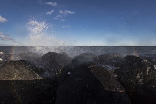 a wave hits stone pier