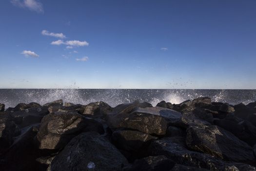 a wave hits stone pier