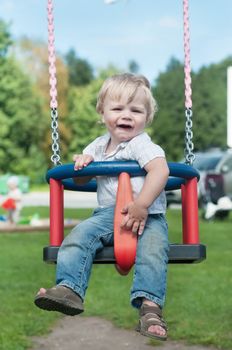 Happy little boy swinging on a swing