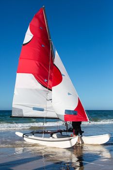 Catamaran sailing vessel with a pretty red and white sail