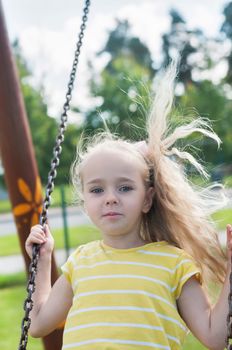 Happy little girl swinging on a swing