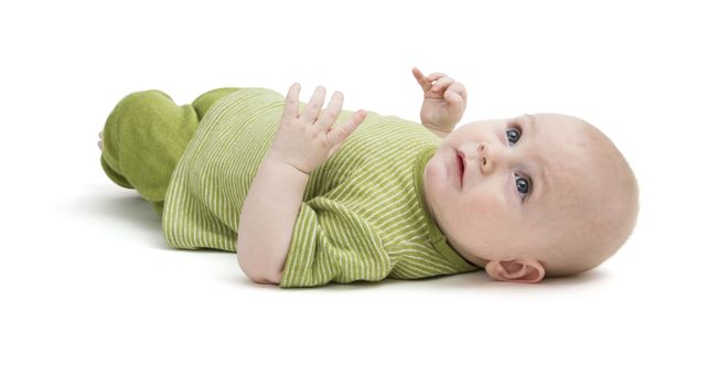 toddler in green clothing laying on back in white background