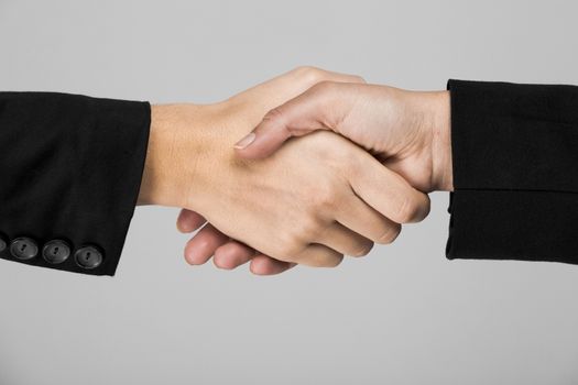 Hands giving a handshake over a gray background