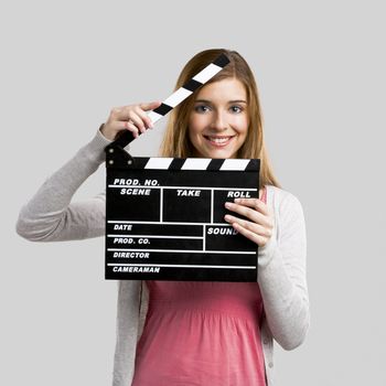 Beautiful blonde woman holding  a clapboard, isolated over gray background