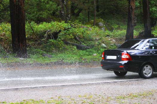Automobile driving on the puddle on a highway