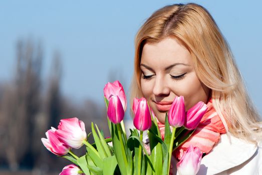 Beautiful young blonde woman with pink tulips