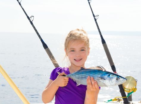 Blond girl fishing bonito Sarda tuna trolling in Mediterranean sea