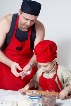 The father with the son work up dough. A transfer of experience . 