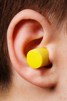 yellow earplug into the ear close up