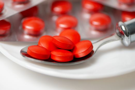 Closeup view of red tablets in silver spoon 