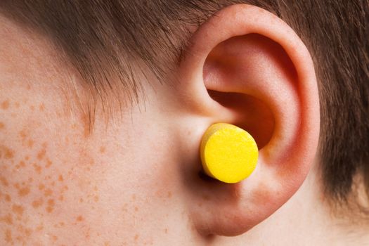 yellow earplug into the ear close up