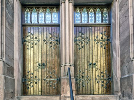 Wooden church doors with beautiful iron work and glass windows. 