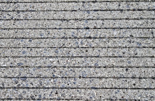 Closeup of sidewalk concrete. Horizontal lines are evenly spaced throughout this interesting texture.